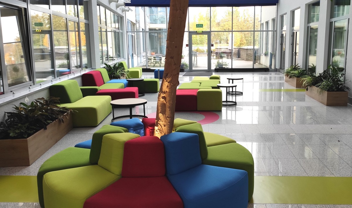 Firma: Bayer
Miasto: Warszawa
Strefa: strefa reprezentcyjno-wypocznkowa w recepcji
Termin realizacji: 2019
Metraż: 16m2 zielonych ścian, 11 donic
Dla jednego z naszych klientów - Firmy Bayer - przygotowaliśmy aranżację wnętrza recepcji w oparciu o geometryczną kompozycję. Prostopadłe ściany pokryte żywymi roślinami stworzyły kompozycję otwartego kwadratu. Bujna i zróżnicowana gatunkowo roślinność doskonale eksponuje wejście do recepcji. Dodatkowo, specjalistyczne oświetlenie wydobywa głębię kolory i strukturę roślin, tworząc jednocześnie warunki do ich rozwoju. Podświetlone logo firmy wkomponowane w roślinność wzmacnia efekt trójwymiarowości.
Na powierzchni biurowca pojawiła się ponadto zieleń doniczkowa m.in. z dwubarwnym epipremium ustawione w linii wzdłuż ścian tworząc naturalne szpaler z żywych roślin. Uzyskana w ten sposób kompozycja roślin jest harmonijna i bardzo dobrze wzmacnia charakter miejsca i funkcję recepcji. Dodatkowo, złożoność tekstur i wybarwienia roślin idealnie podkreślają kolory mebli. Zastosowanie roślinności właśnie w tej części biura firmy daje oczekującym Gościom poczucie bezpieczeństwa i chwilę relaksu, jakie często daje nam kontakt z naturą.